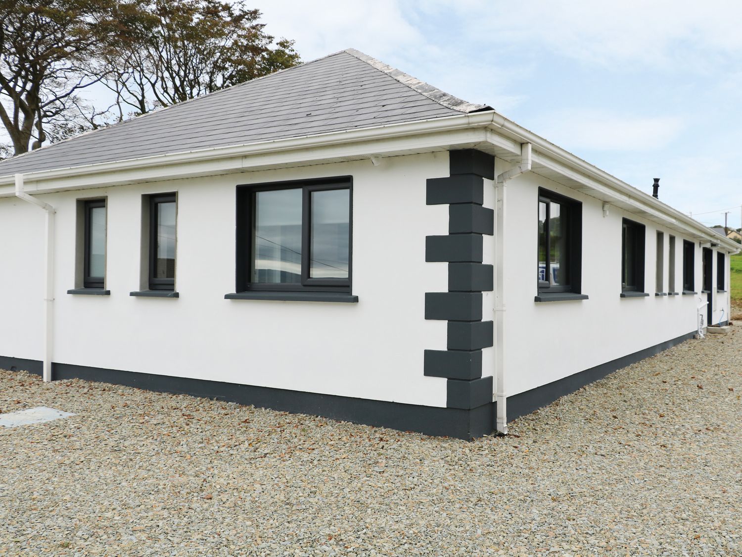 An exterior view of a single story building with white walls and black window frames at Gatehouse in Moville County Donegal