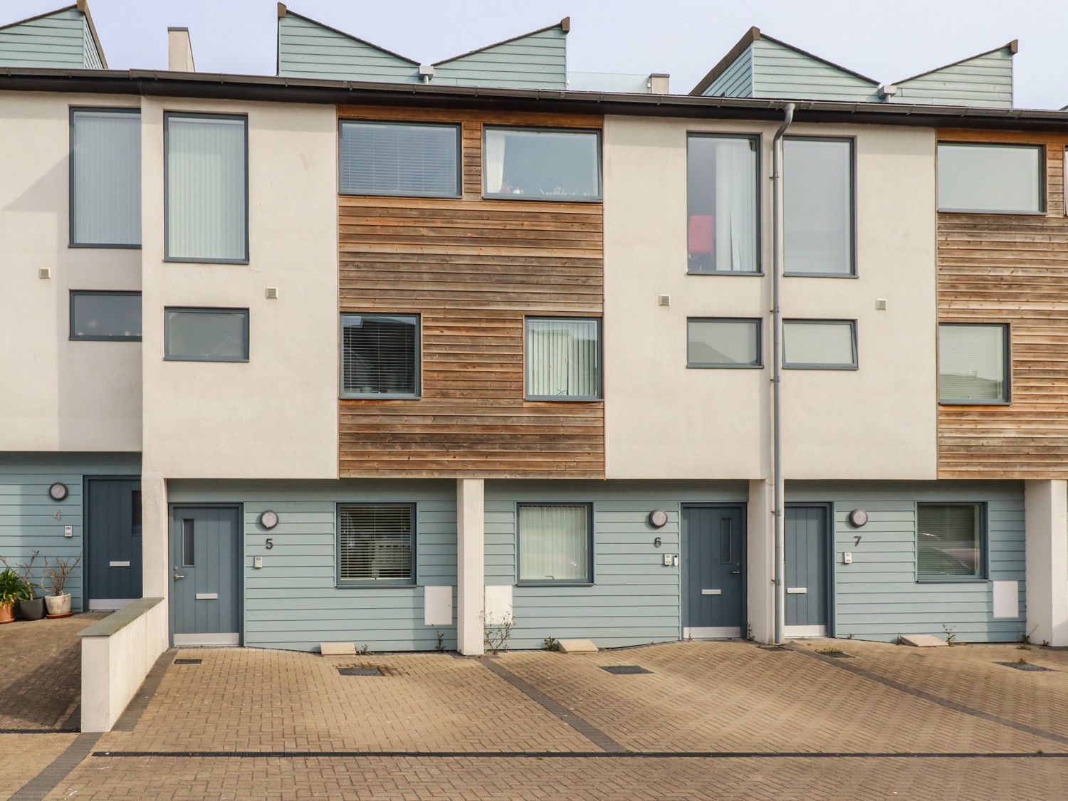 A row of modern townhouses with blue doors and parking spaces at 5 Quay Court in Newquay