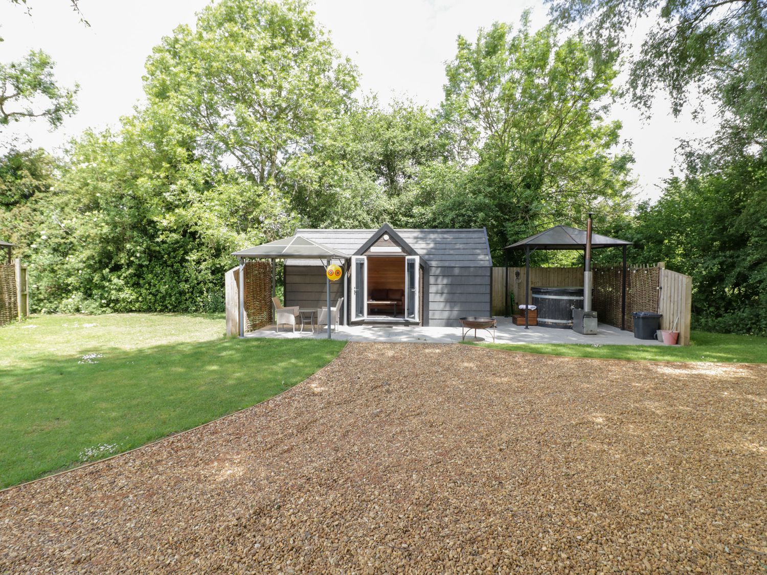 A garden with a shed and outdoor seating at Willow Lodge At Bridge Lake Farm & Fishery Chacombe