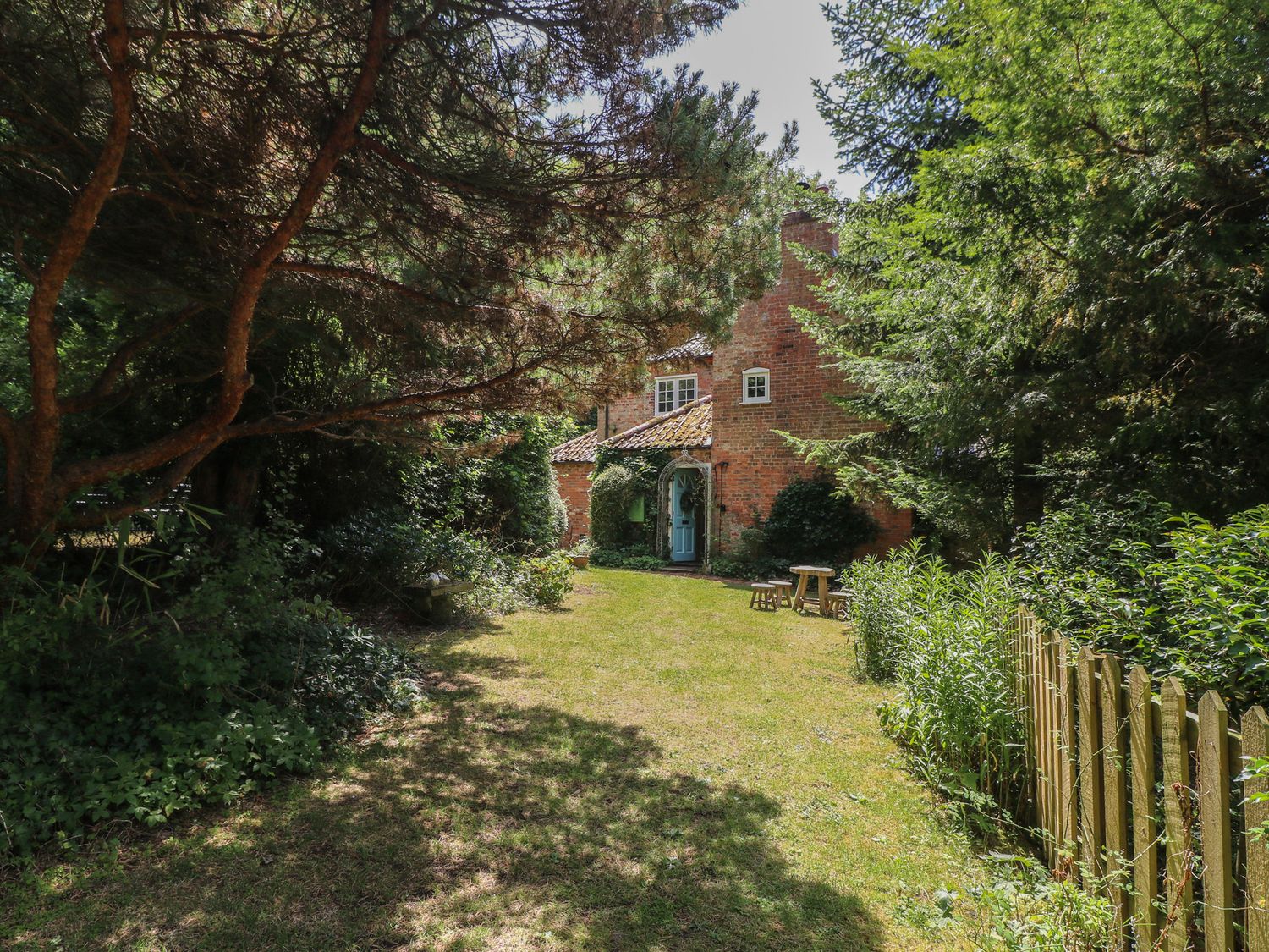 A house and garden with trees and a fence at Sunny Cottage in Grantham
