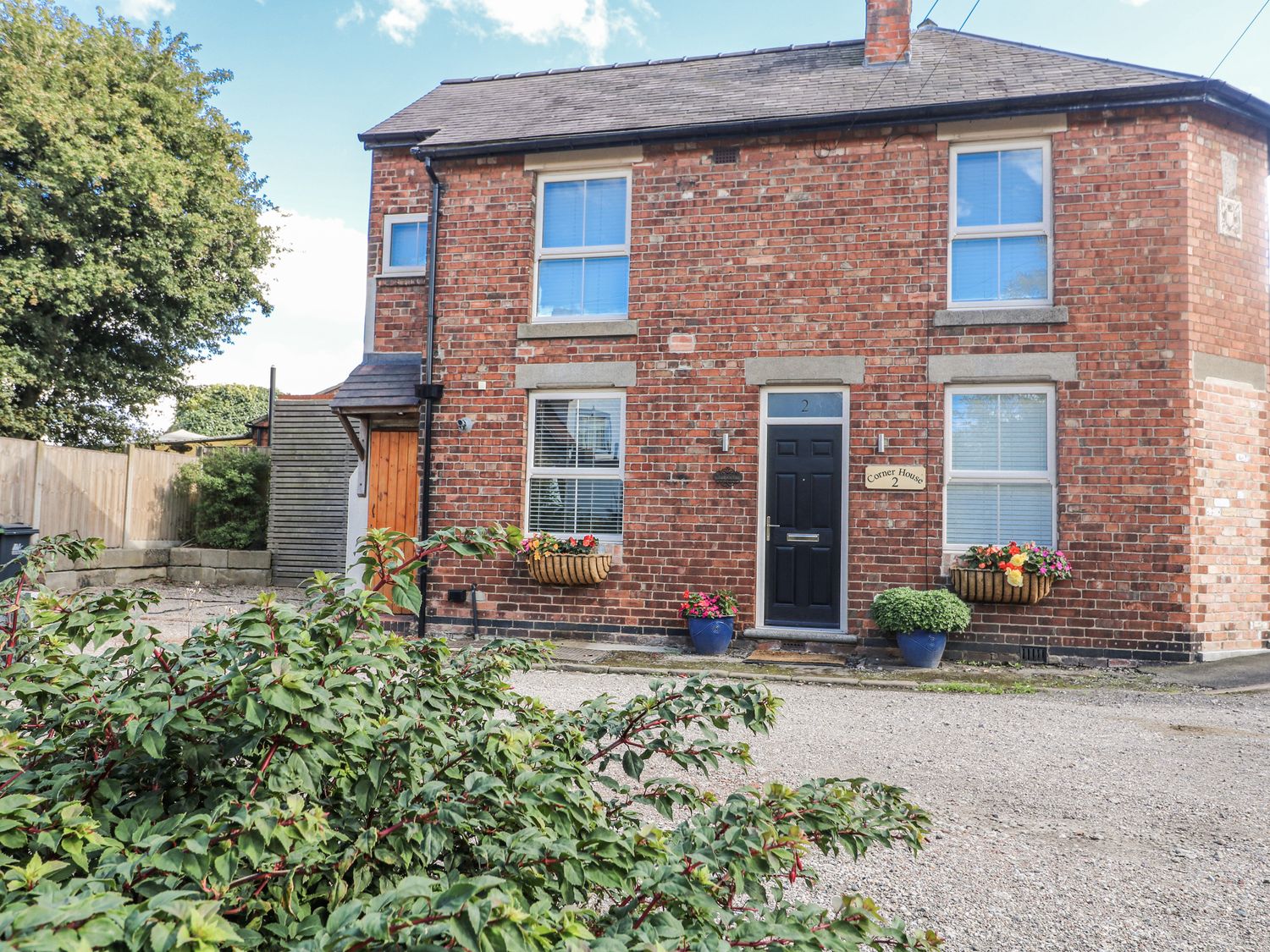 A brick house with flower pots outside at Corner House Cottage in Mapperley Village