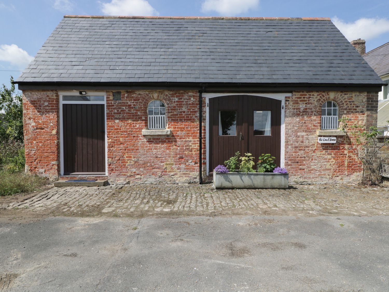 A building with two doors and a planter at Coach House in Swindon