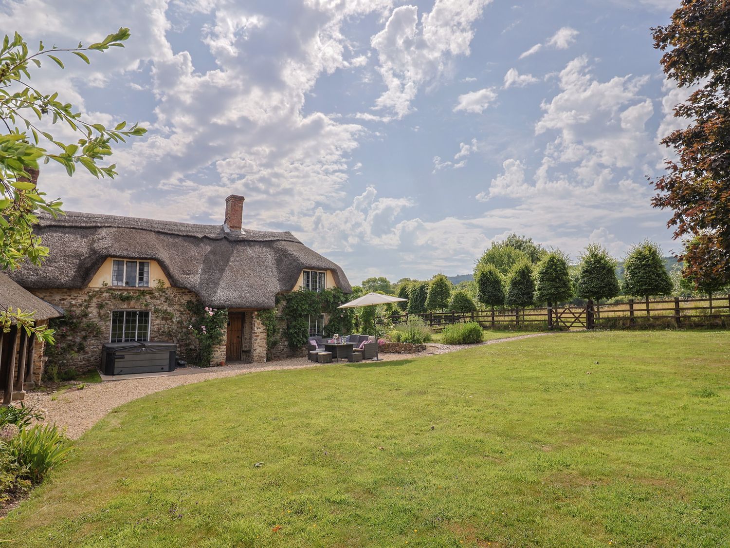 A garden with a thatched house outdoor furniture and trees at Garden View in Wellington
