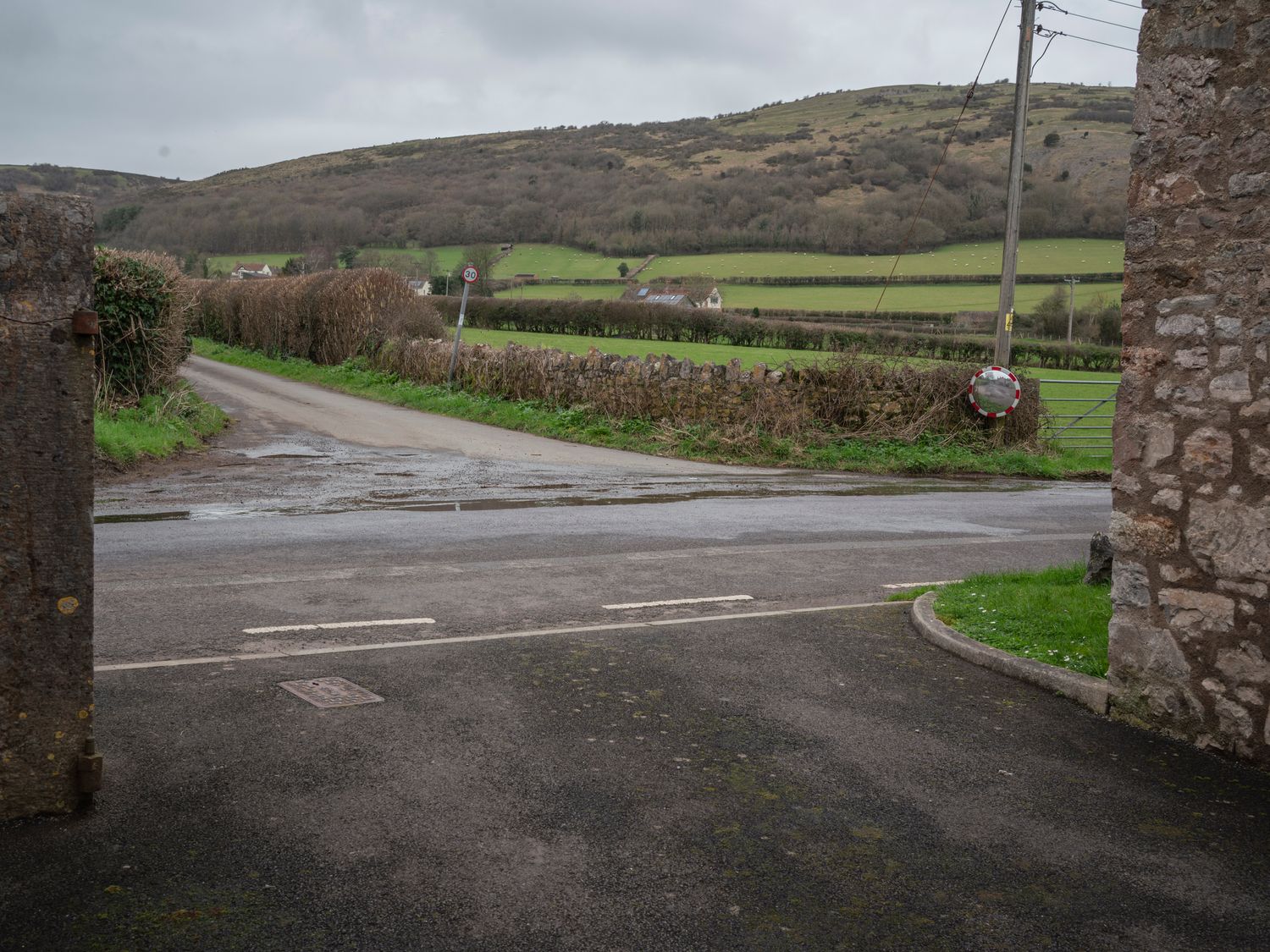 A rural road with hedges and stone walls leading to fields and hills at Crooks in Axbridge