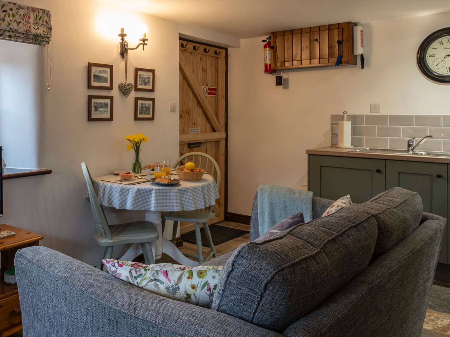 A small kitchen and dining area with a table set for breakfast and a gray sofa at Crooks Axbridge
