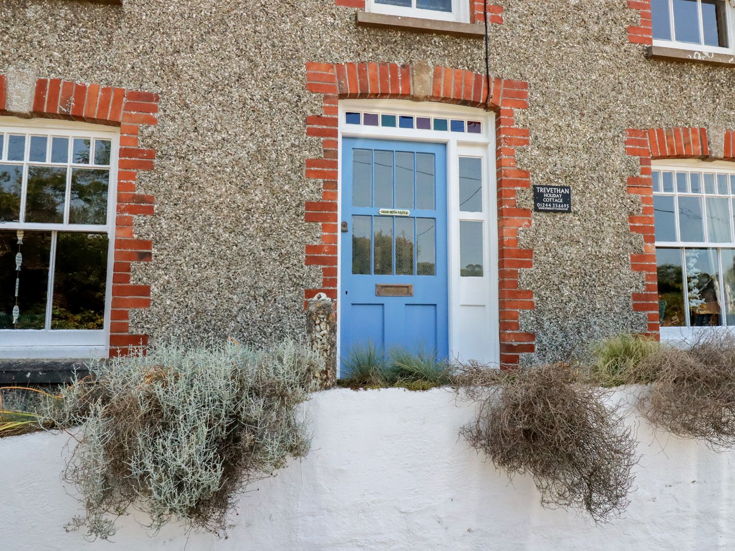 A blue door and window on a stone wall at Trevethen Cottage Crantock