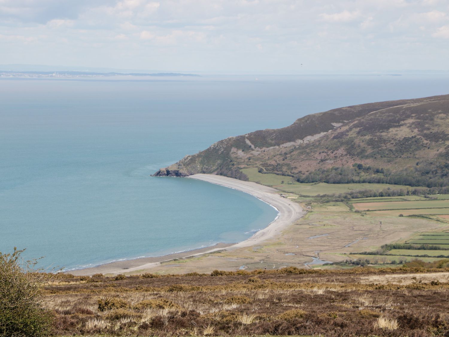 A coastal landscape with a curved beach fields and hills at Small Piece in Porlock