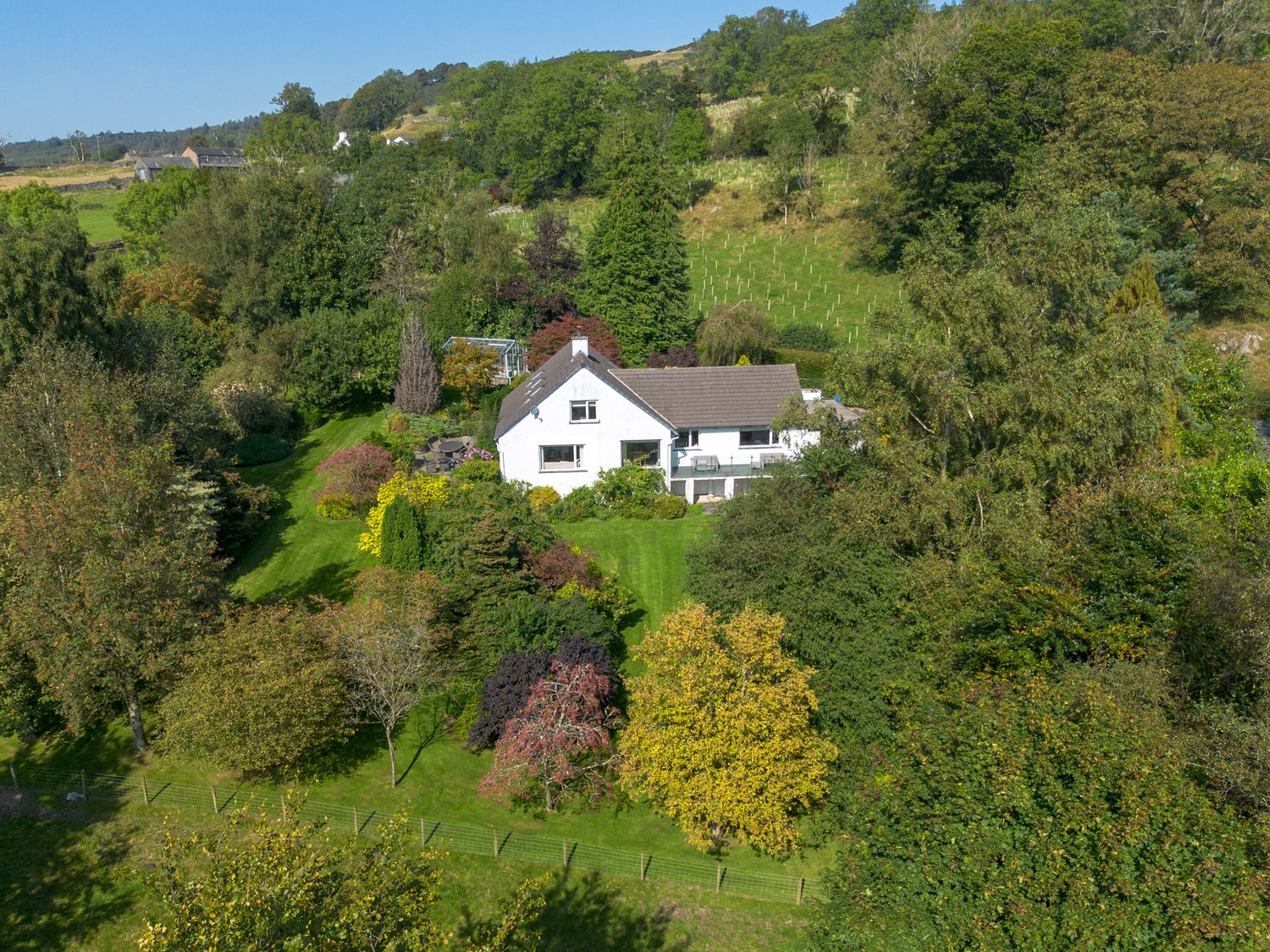 A white house surrounded by trees and greenery in a rural area at Scarsdale in Crosthwaite