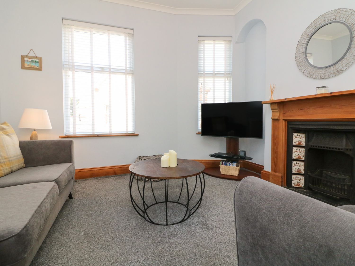 A living room with grey sofas a round coffee table candles a television and a fireplace at Torrs Walk View in Ilfracombe