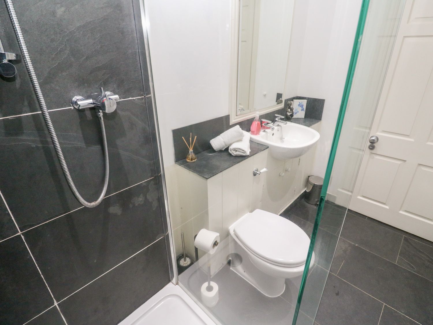 A bathroom with a shower area toilet sink mirror and towels at No 1 The Hinges in Crantock