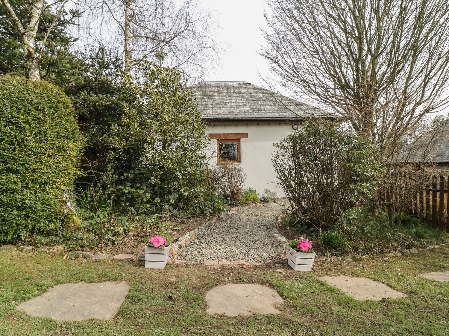 A gravel pathway leading to a small building surrounded by bushes and trees at Little Torr in Drewsteignton
