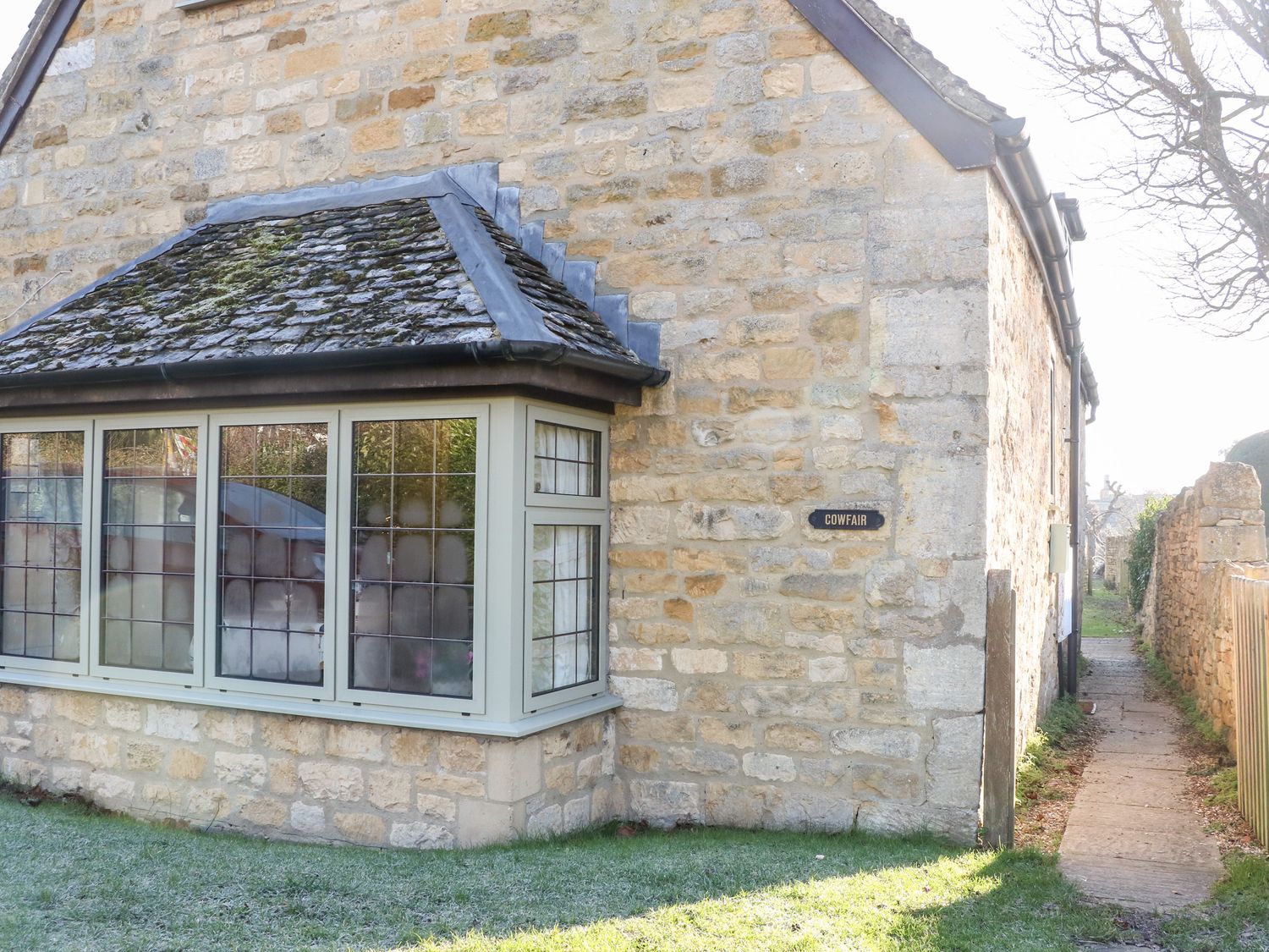 Stone cottage with leaded windows and a small path beside it at Cowfair Cottage in Chipping Campden