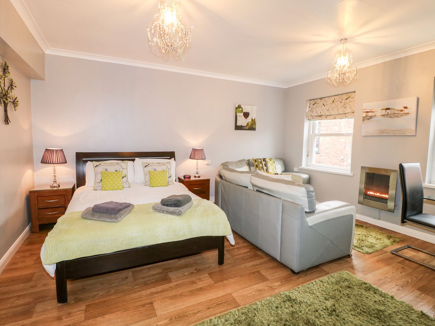 A bedroom with a bed sofa side tables lamps rug and fireplace at Grayz Studio in Lincoln