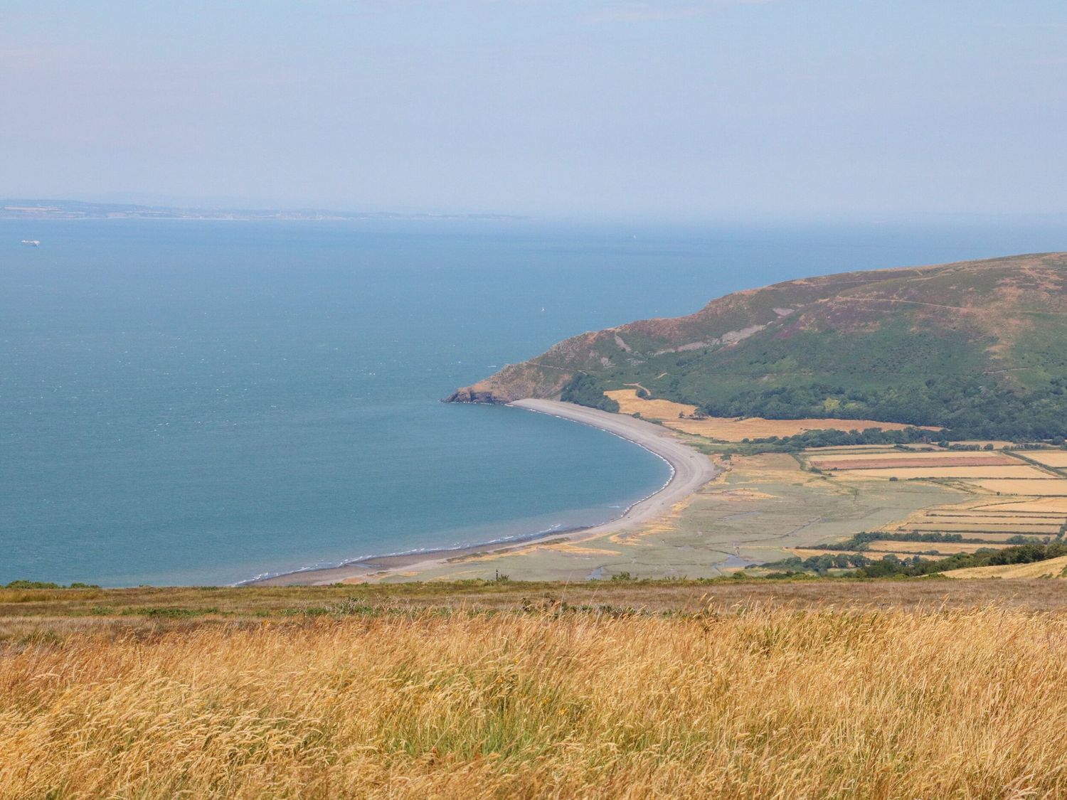 A coastal landscape with a curved beach hills and fields at The Cadeleigh in Cadeleigh near Tiverton