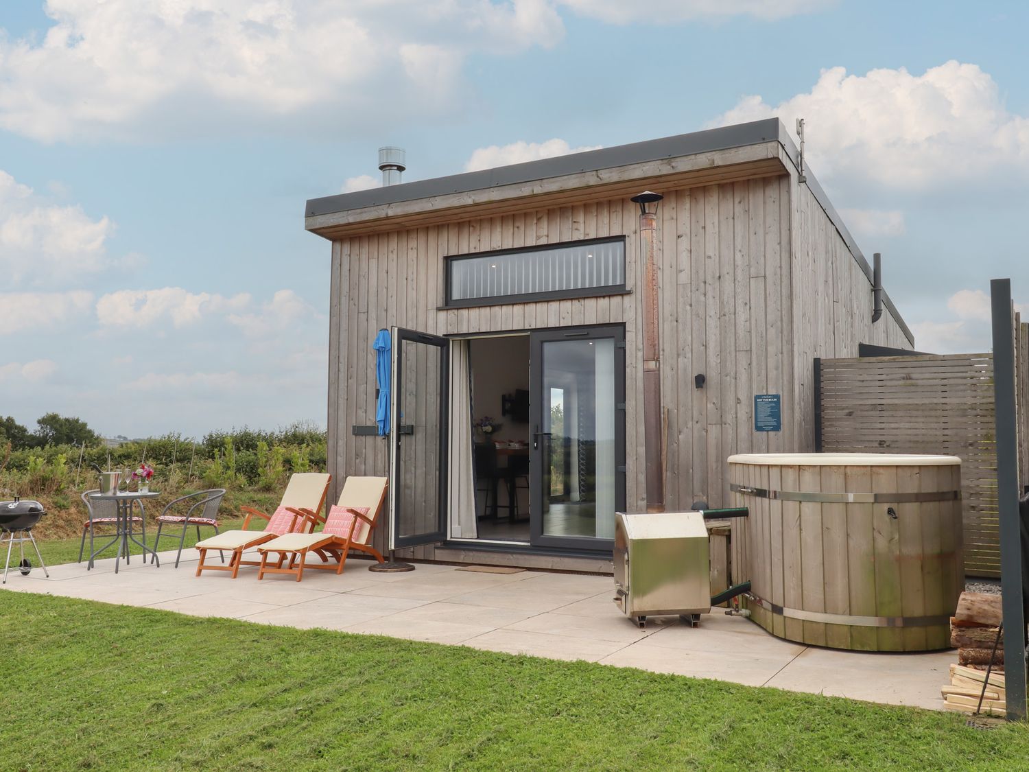 An outdoor area with a hot tub, seating and a grill at The Cadeleigh in Cadeleigh near Tiverton