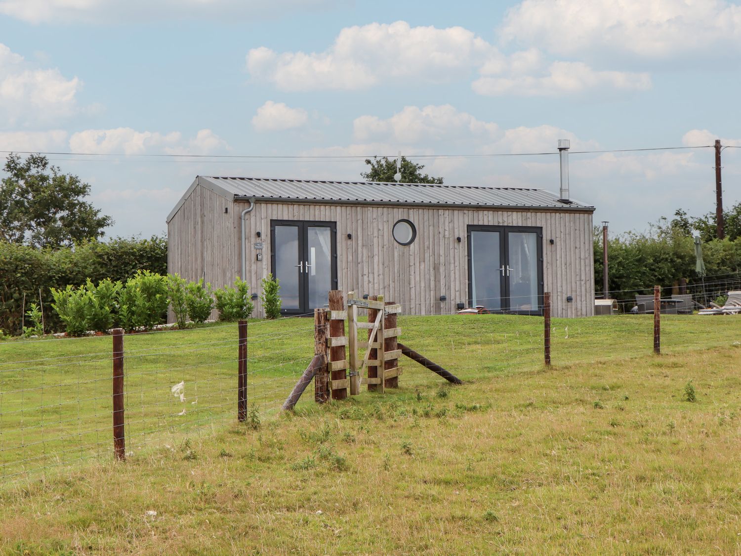 A house with a wooden exterior and a fence at The Pennymoor in Cadeleigh near Tiverton