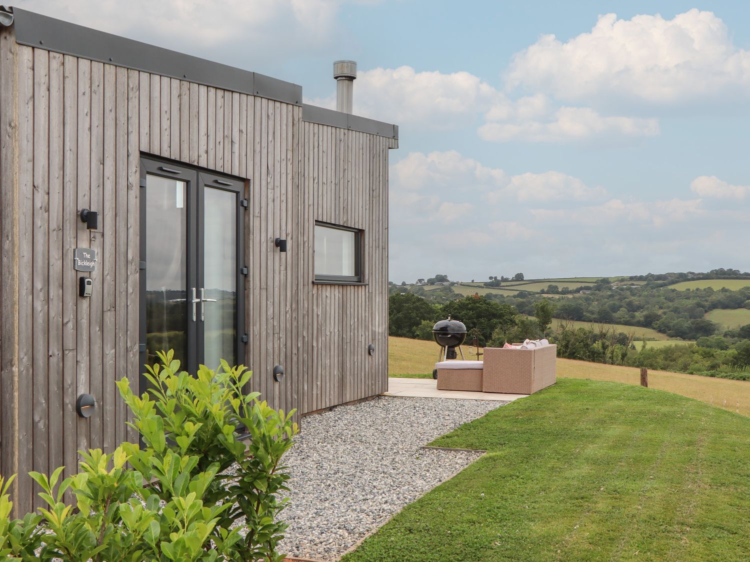 An outdoor area with a wooden cabin and seating at The Bickleigh in Cadeleigh near Tiverton