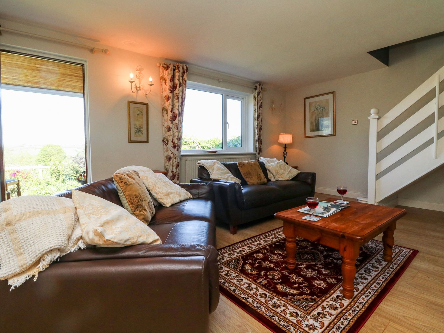 A living room with two brown leather sofas a wooden coffee table with drinks on a red patterned rug at Ash Tree Cottage in Bradworthy