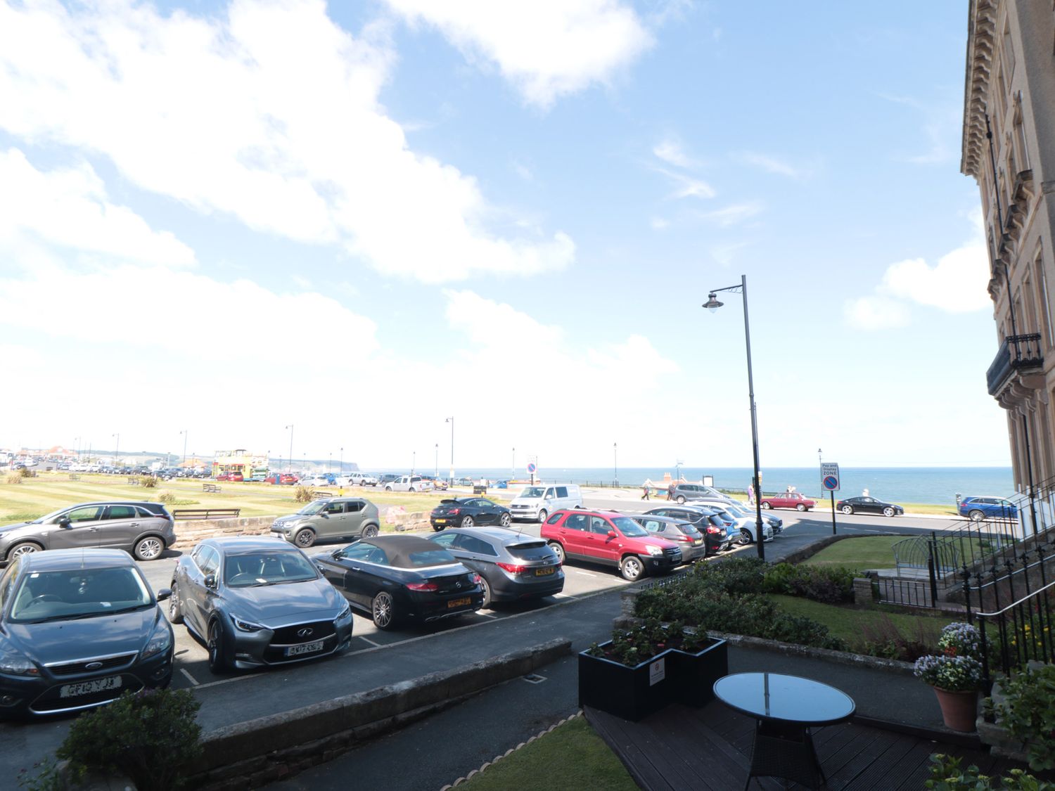 A parking lot by the sea with cars and a building on the right at Sunset View in Whitby