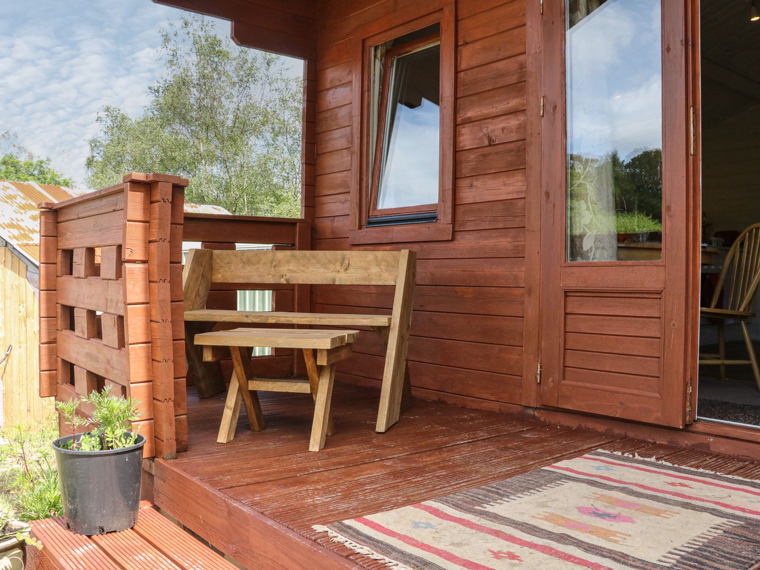 A wooden porch with a bench and small table next to a door and window at The Cabin Lowley Brook Farm Rezare near Launceston