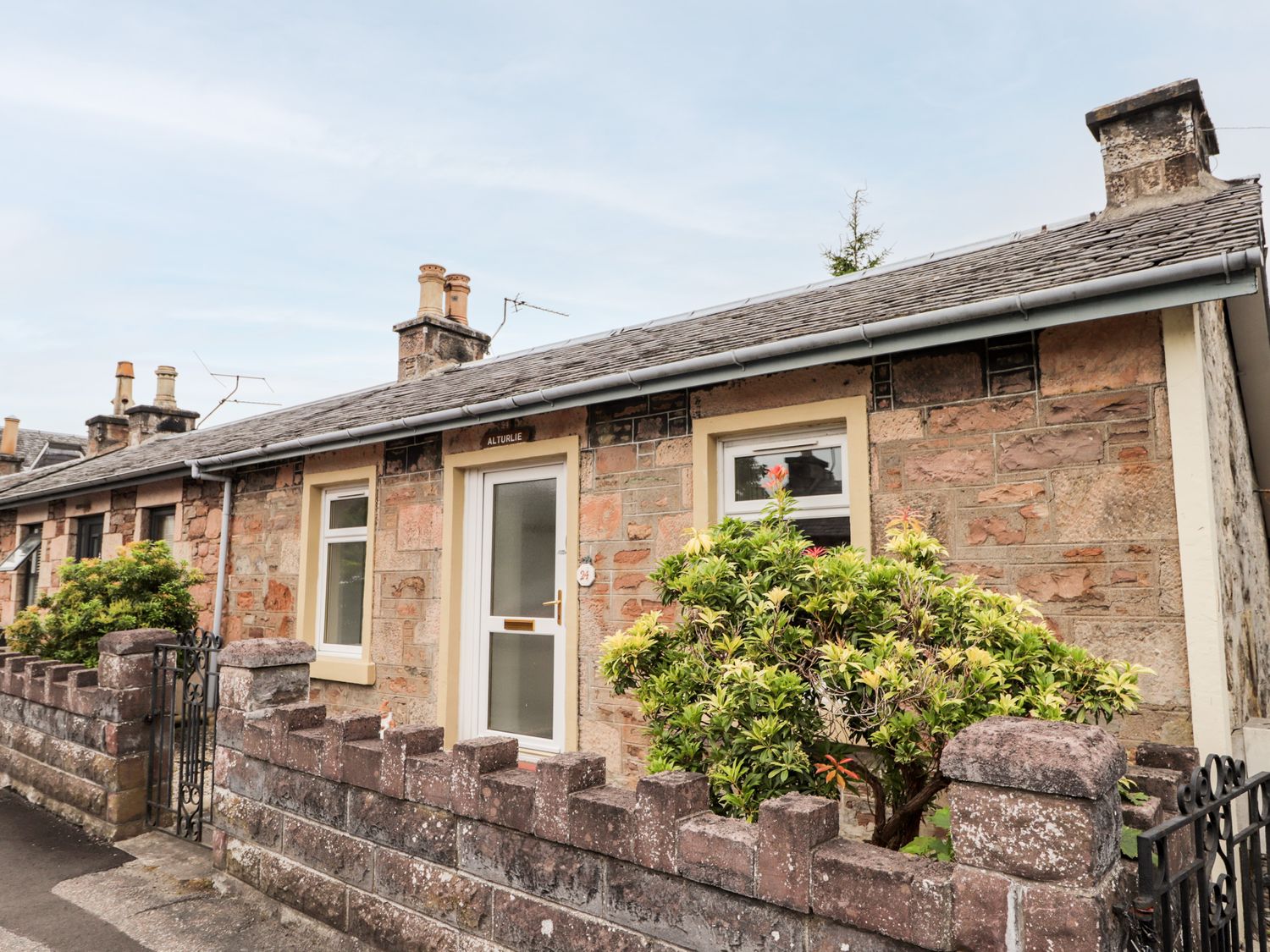 A stone house with a small front garden and a gated stone wall at Alturlie in Inverness