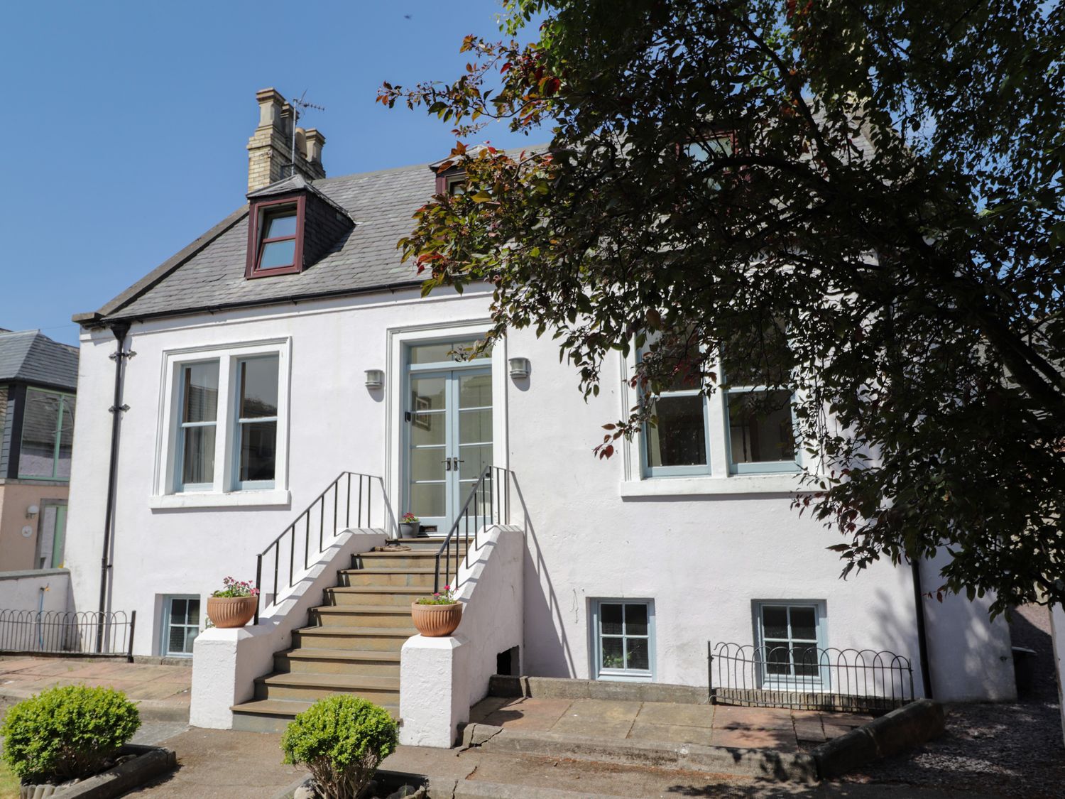 The exterior of a white house with stairs leading to a front door and surrounded by bushes at Mary Ann Villa in Inverness