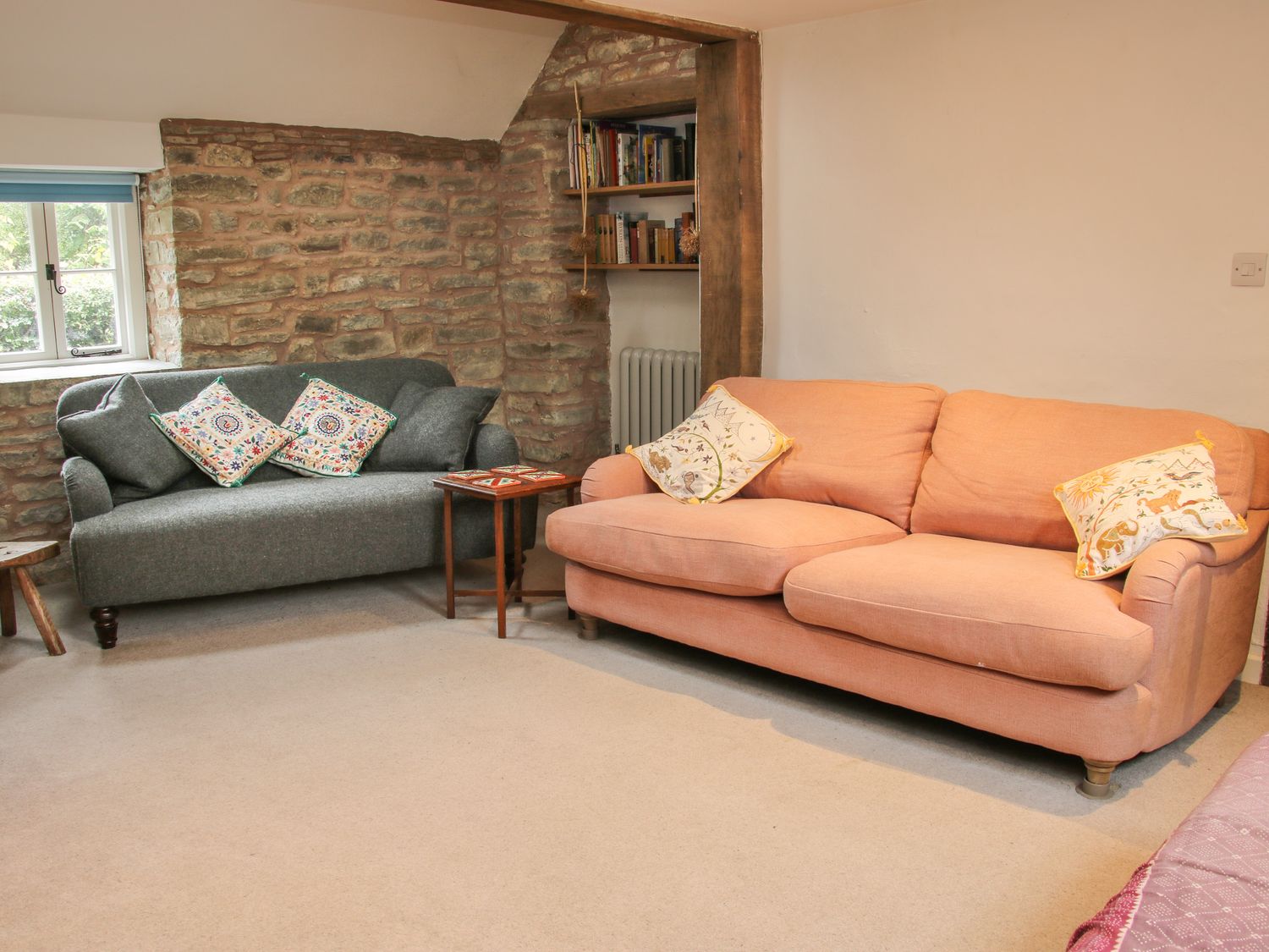 A living room with two sofas and a small table by a stone wall at Denbigh Hall in Presteigne