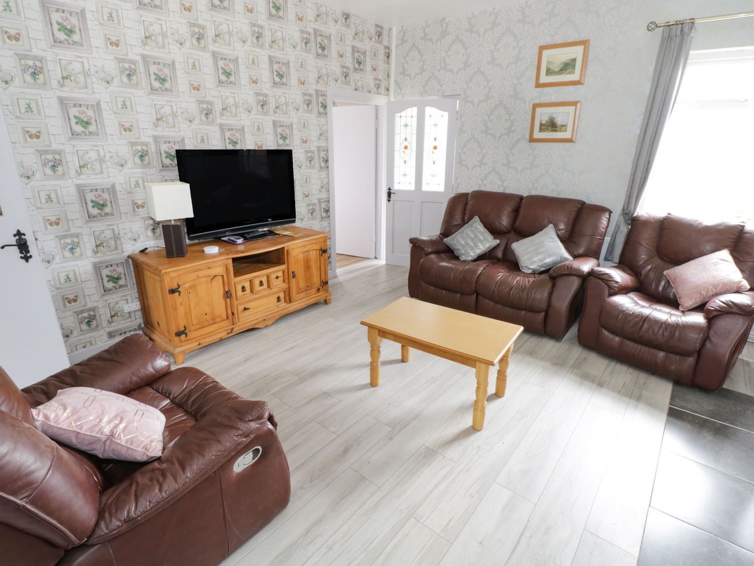 A living room with brown leather sofas a wooden coffee table a wooden TV stand with a television and a lamp at Sean Bhaile in Glenisland near Castlebar County Mayo