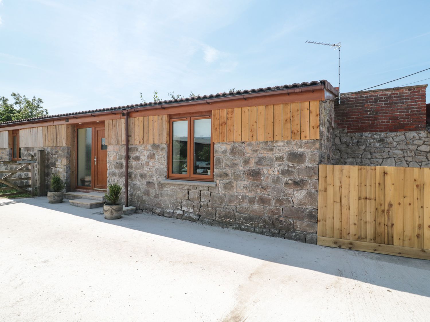 Exterior view of a stone and wood building with a wooden door and window at The Old Cow Shed in Banwell