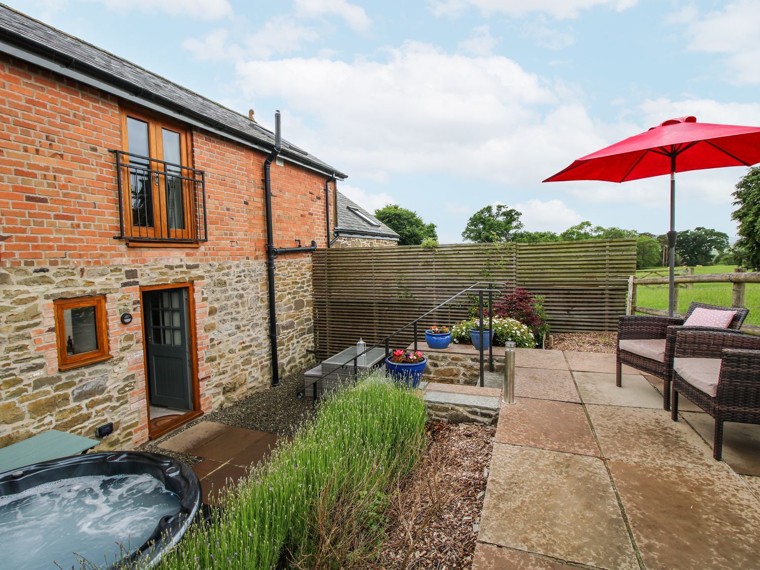 An outdoor space with a hot tub and seating at Meadow Barn in Aston On Clun