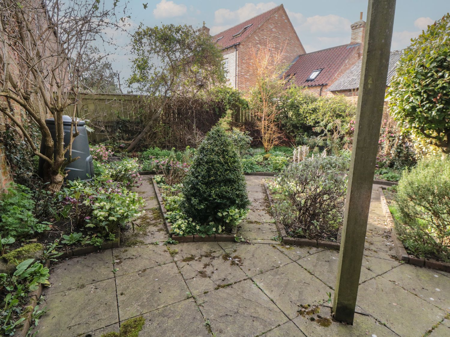 A garden with paved paths and various plants and bushes at Wren's Nest in Thirsk