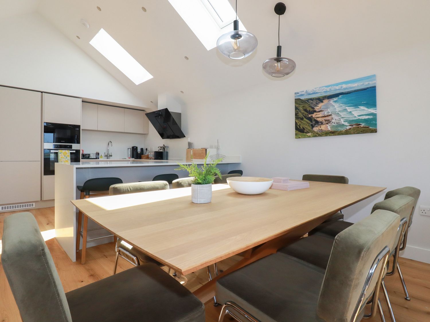 A dining table with chairs and a kitchen area in the background at Porth Cove in Porth
