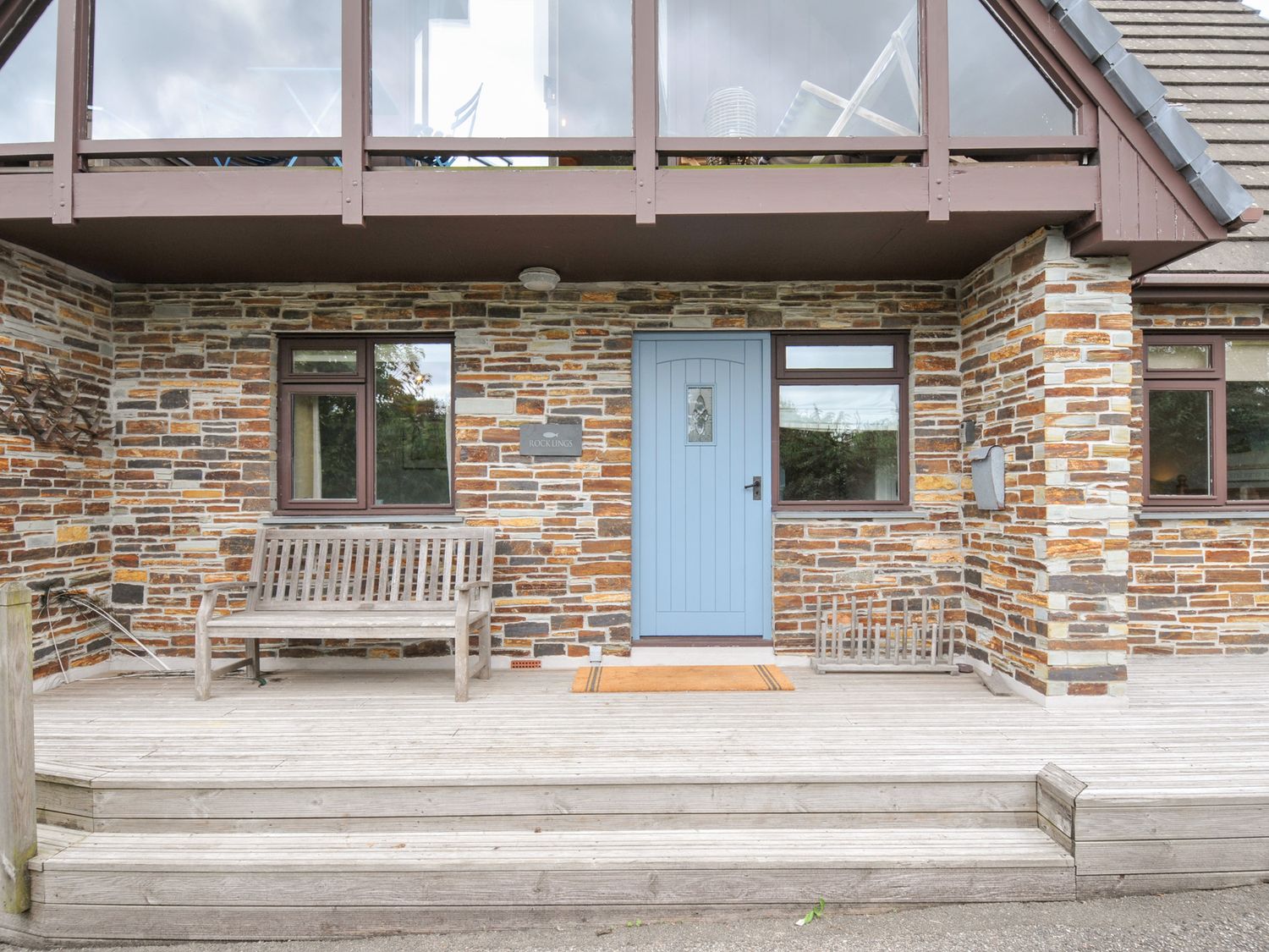 A front entry with a blue door and wooden bench at Rocklings in Rock