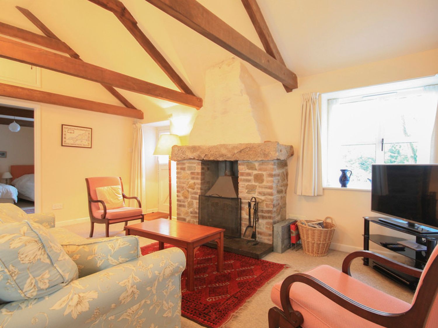 A living room with exposed wooden beams a stone fireplace and seating at Mill Pond in Rock