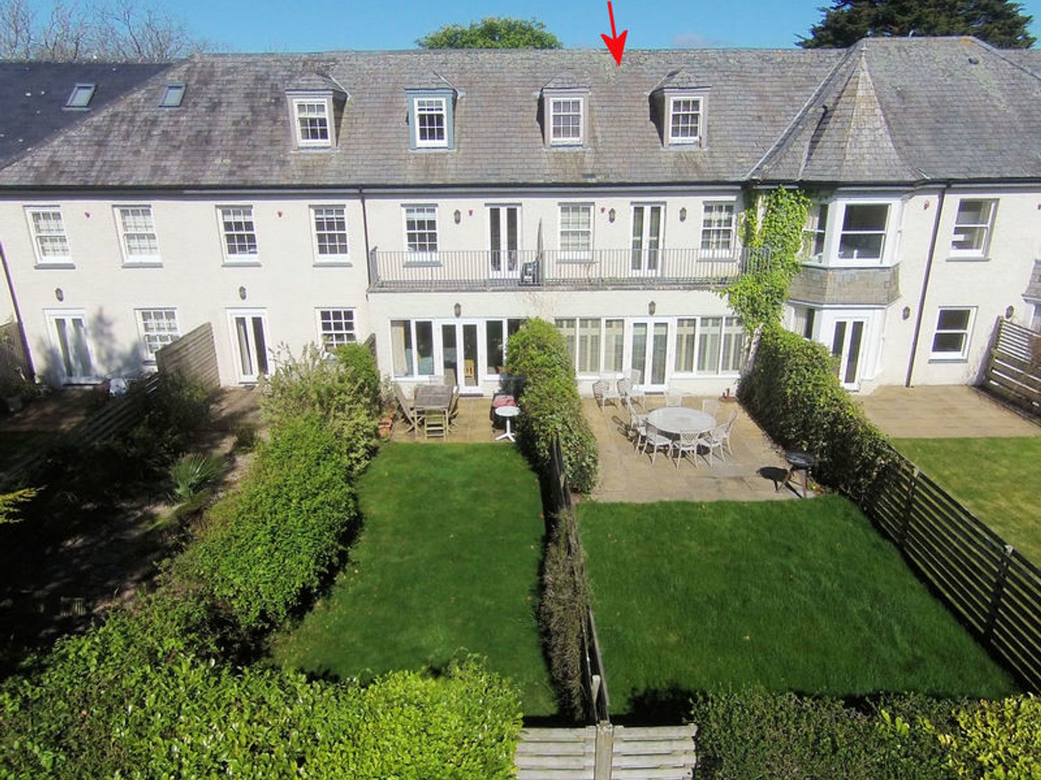 A row of white two-story houses with backyards and garden furniture at Lowenna Manor 5 in Rock