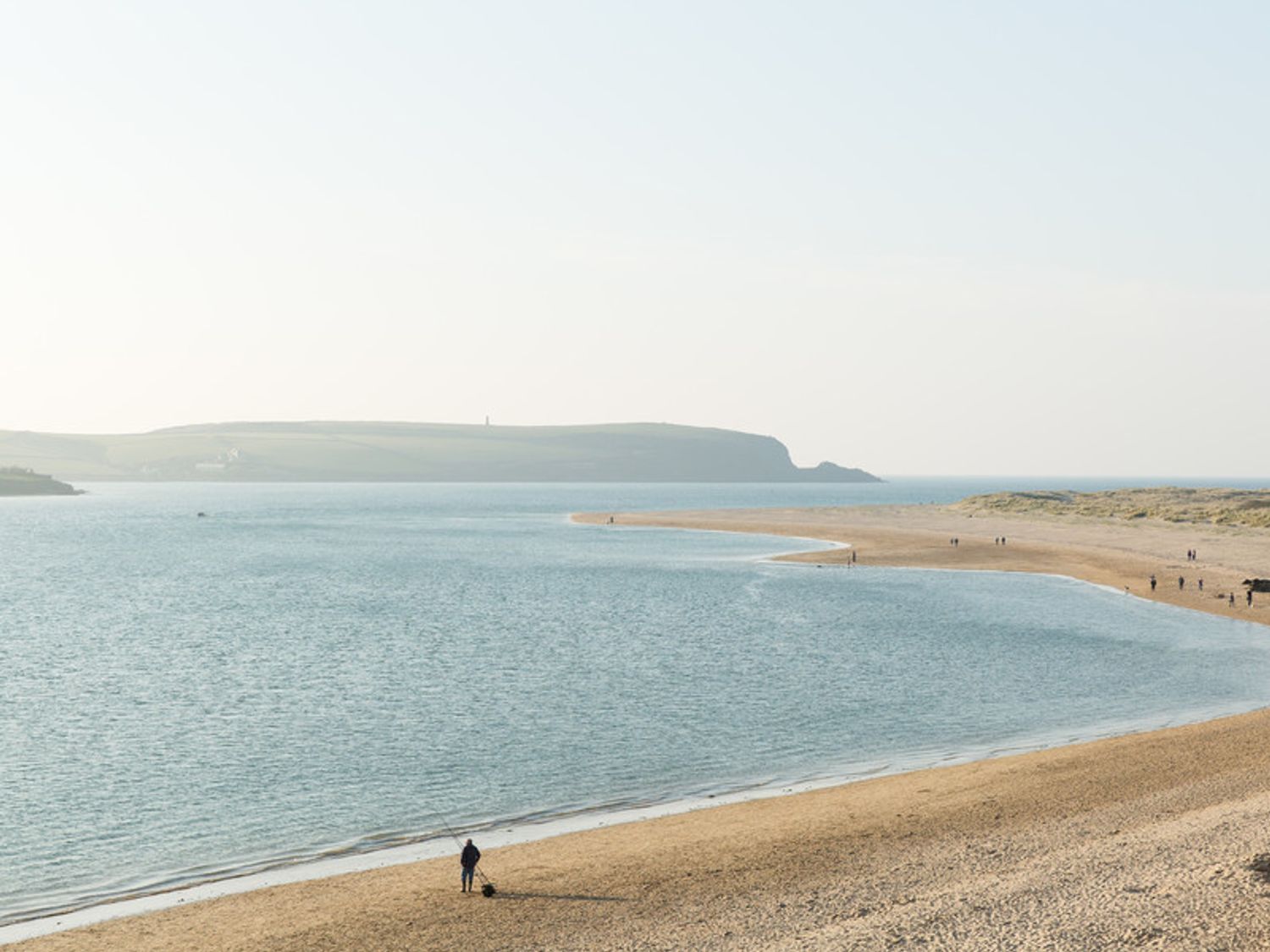 A beach with people on the sand and a person fishing at Lowenna Manor 5 in Rock