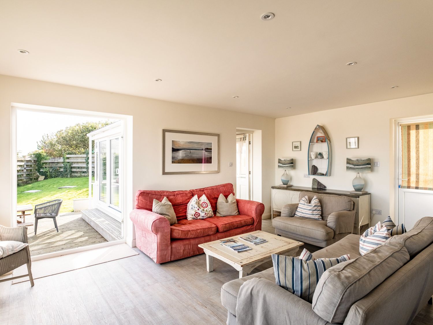 A living room with sofas and a coffee table next to a garden at Atlantis in Polzeath