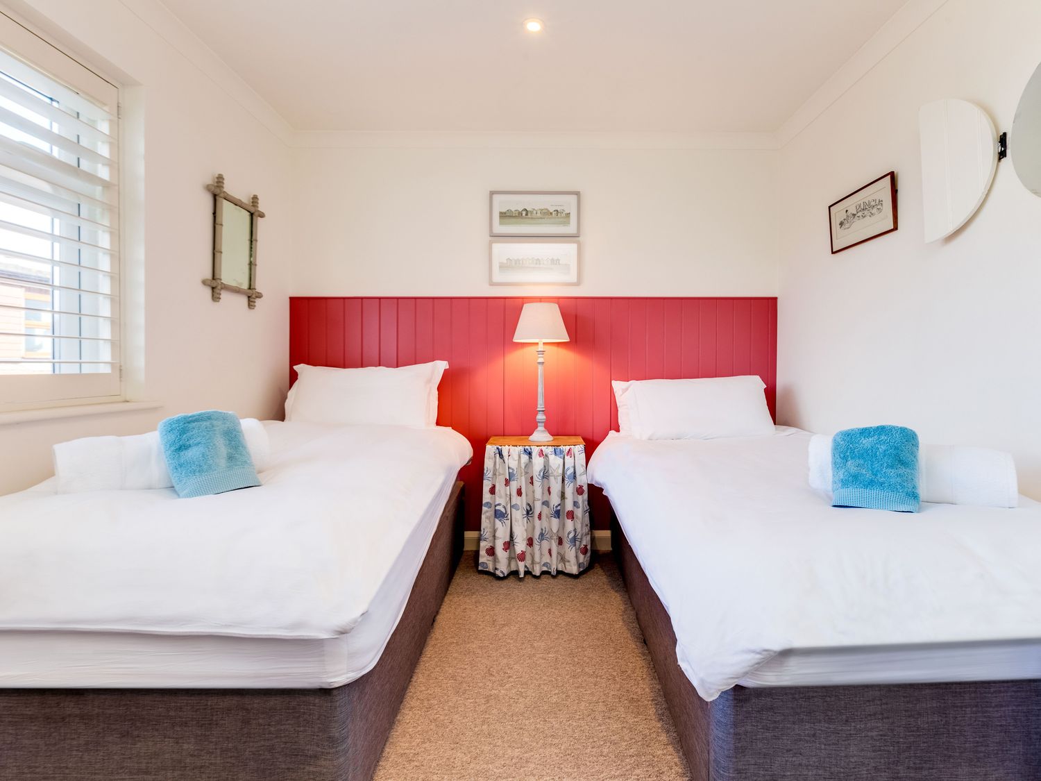 A bedroom with two single beds a red headboard and a lamp on a table at Atlantis in Polzeath