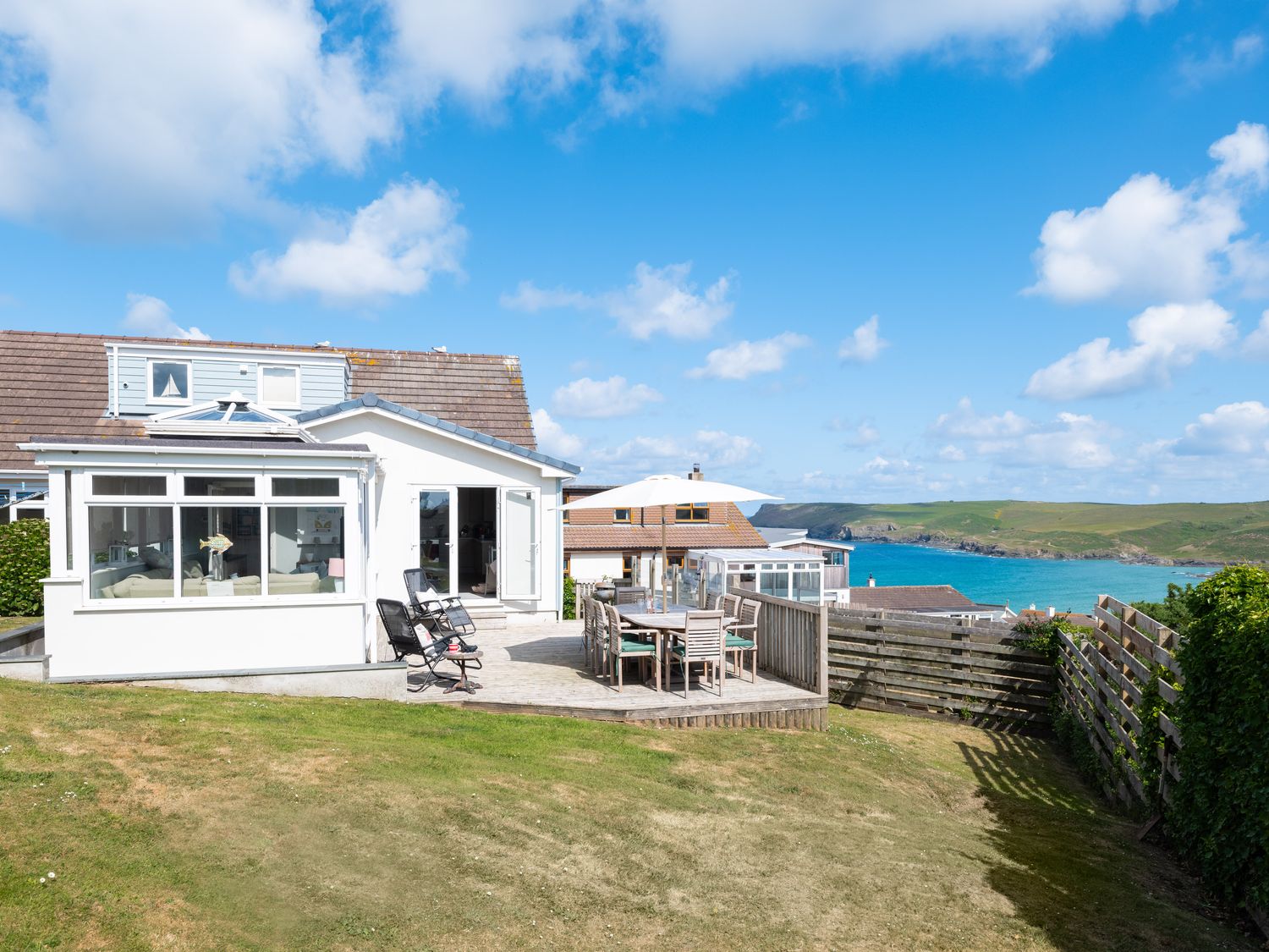 A house with a patio and outdoor dining furniture overlooking the sea at Atlantis in Polzeath