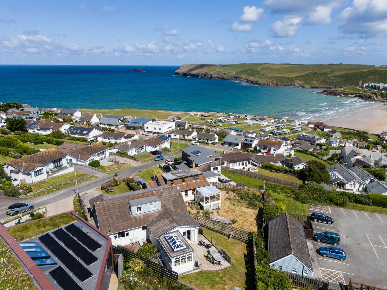 A coastal village with houses roads a parking lot and a bay with a beach at Atlantis in Polzeath