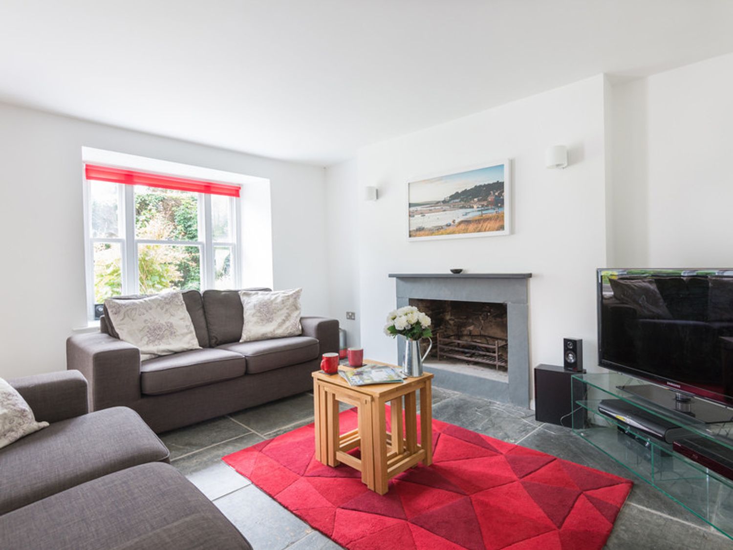 A living room with two gray sofas a wooden coffee table a red rug a fireplace and a television at Conifers in Rock