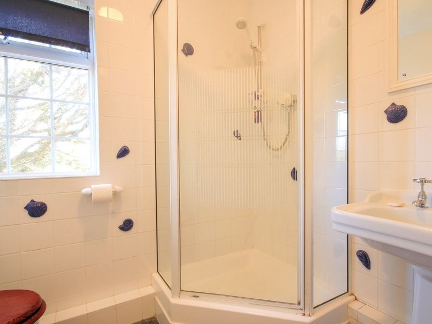 A bathroom with a shower enclosure a sink and a window at Maylands in Port Isaac