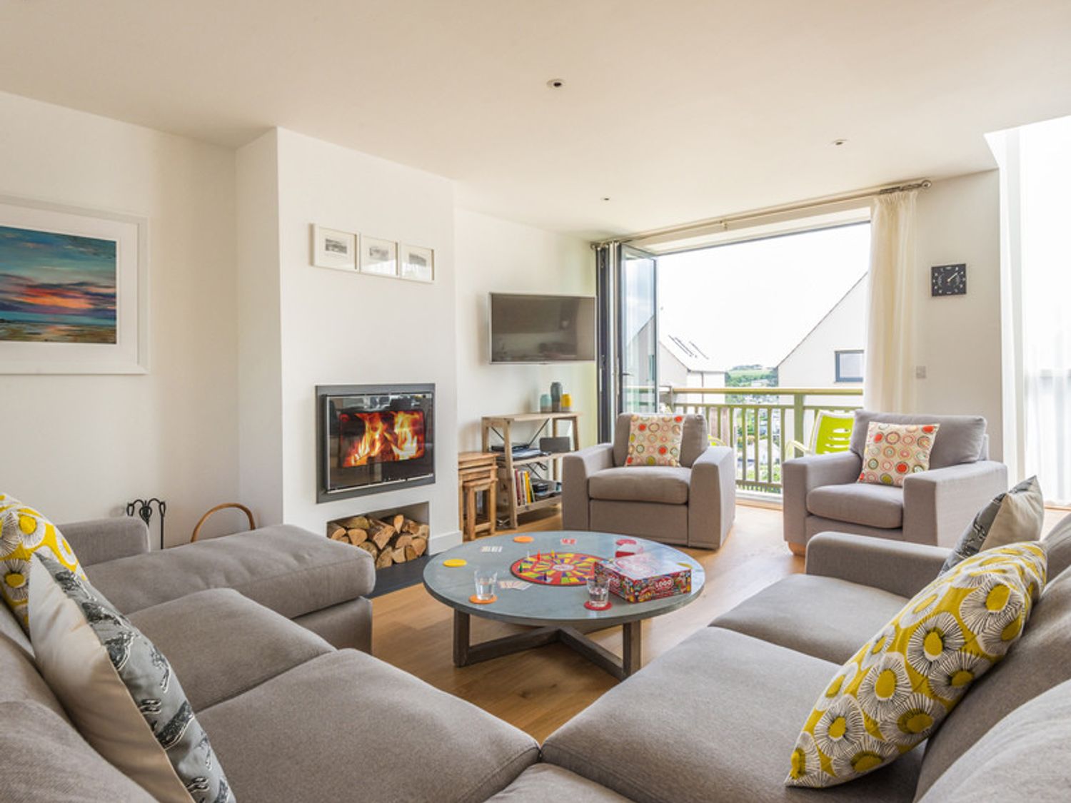 A living room with a fireplace a television and a round table with a board game at Rainer Rocks in Polzeath