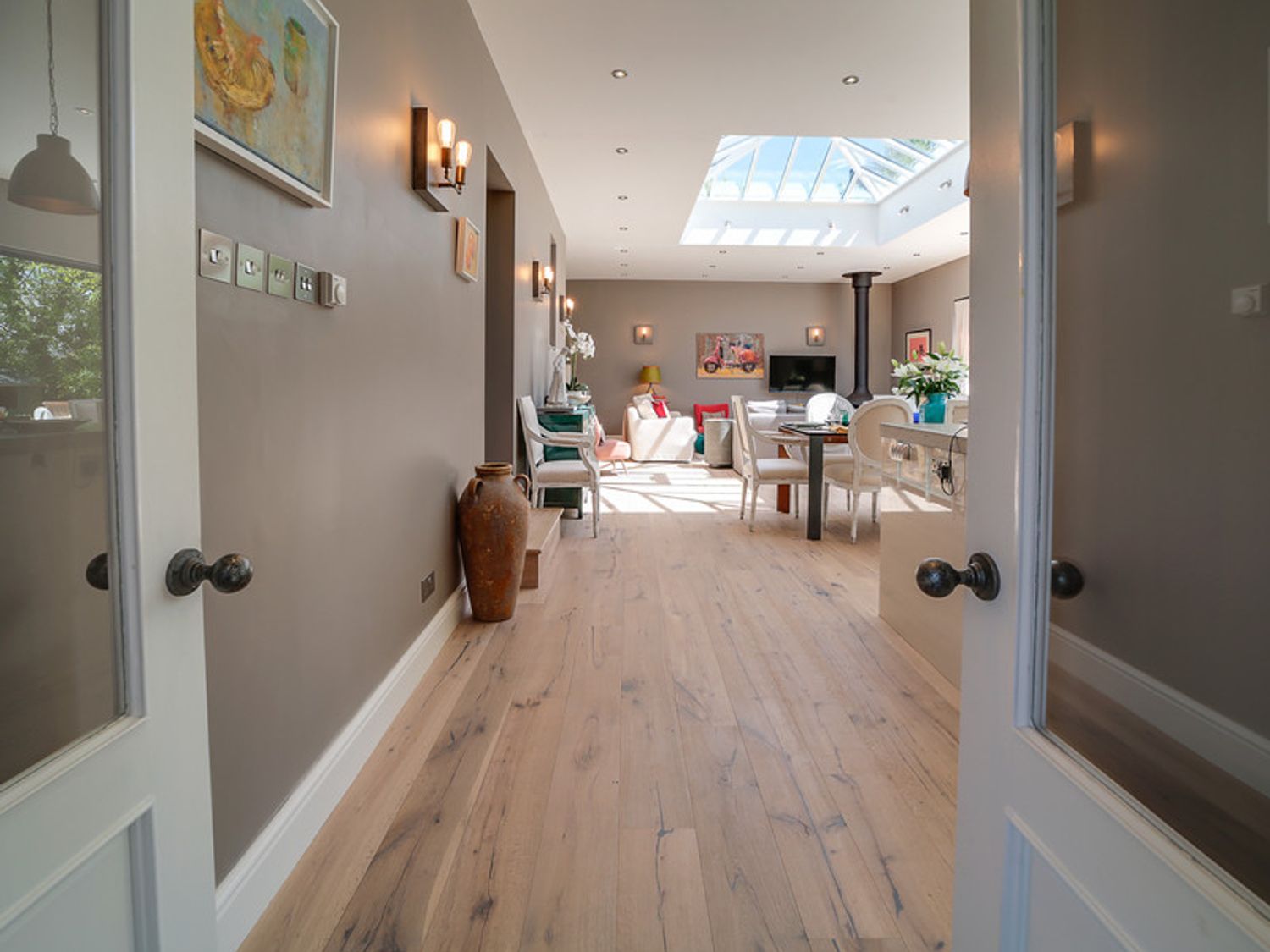 A view through open double doors into a living and dining area with wooden floors skylight and furniture at Trevanion in Rock