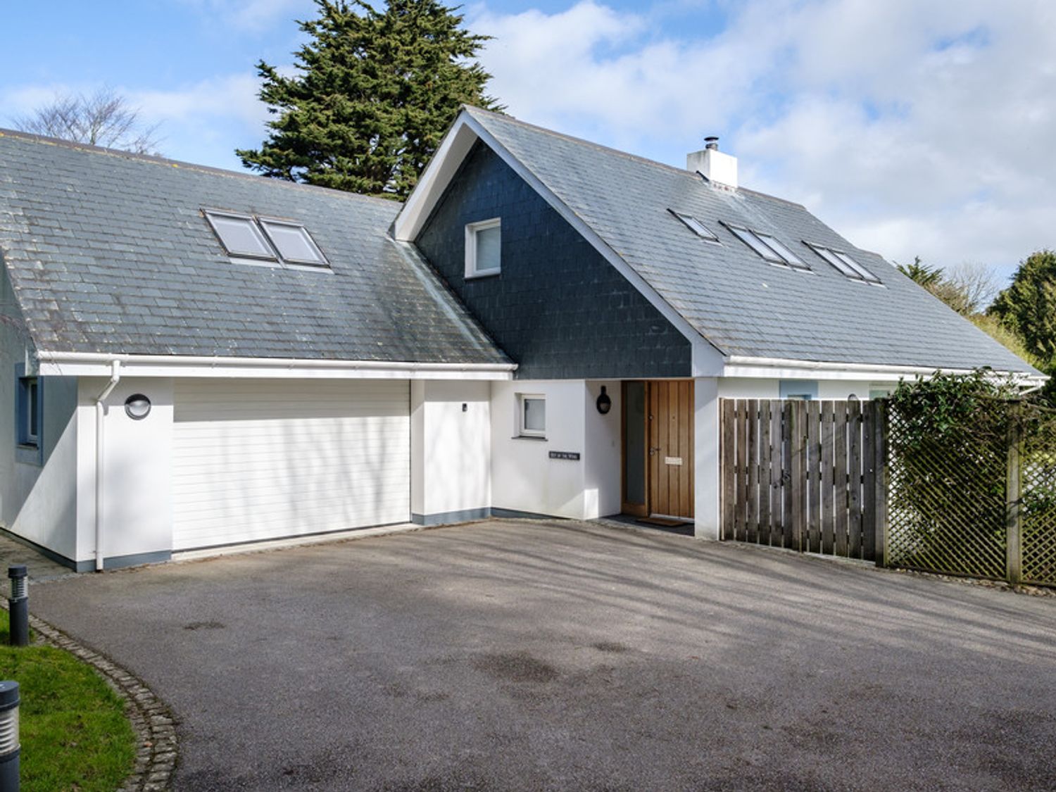 A house with a large sloped roof garage door driveway and wooden front door at Out of the Wind in Rock