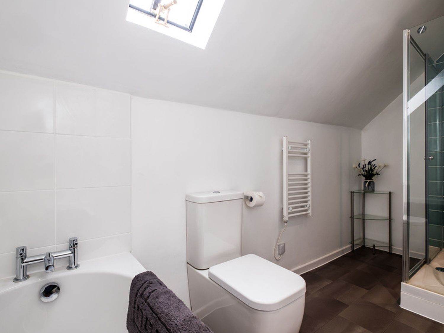 A bathroom with a bathtub toilet towel rack and glass shower at Pinewood 14 in Polzeath
