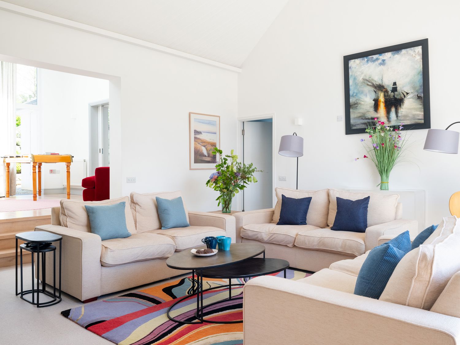 A living room with beige sofas and blue cushions a colorful rug and paintings on the wall at Landers Field in Rock