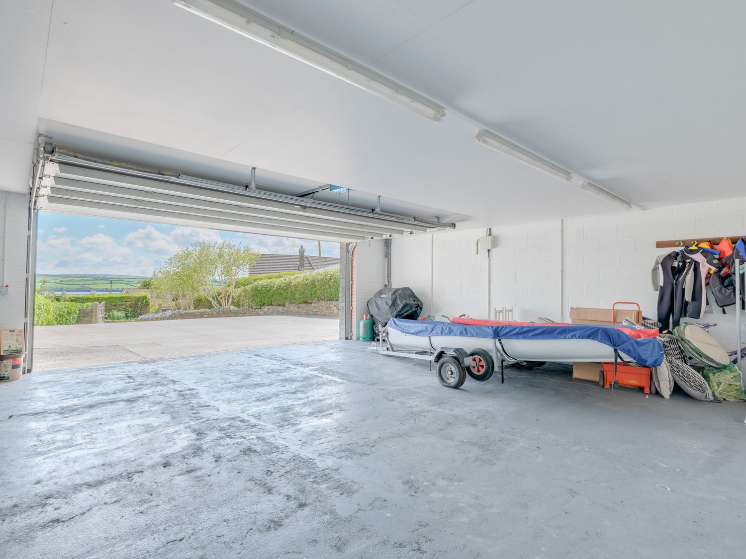 A garage with an open door showing a boat on a trailer wetsuits and storage boxes at Landers Field in Rock