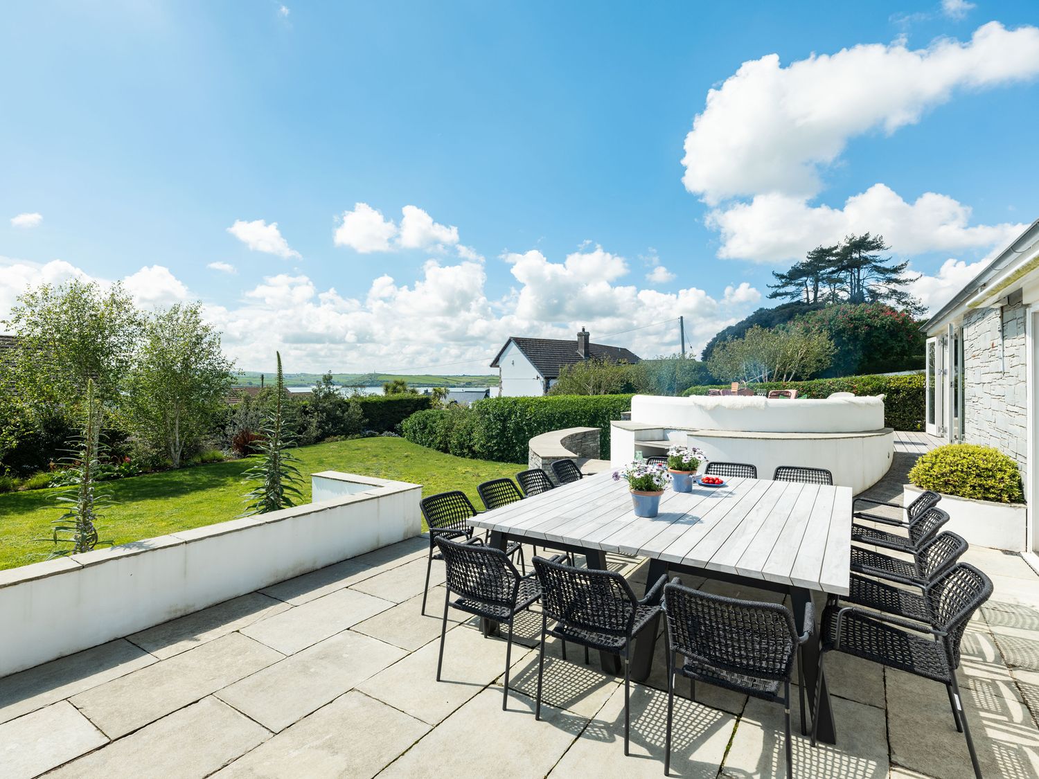 An outdoor patio with a dining table and chairs overlooking a garden and neighboring houses at Landers Field in Rock