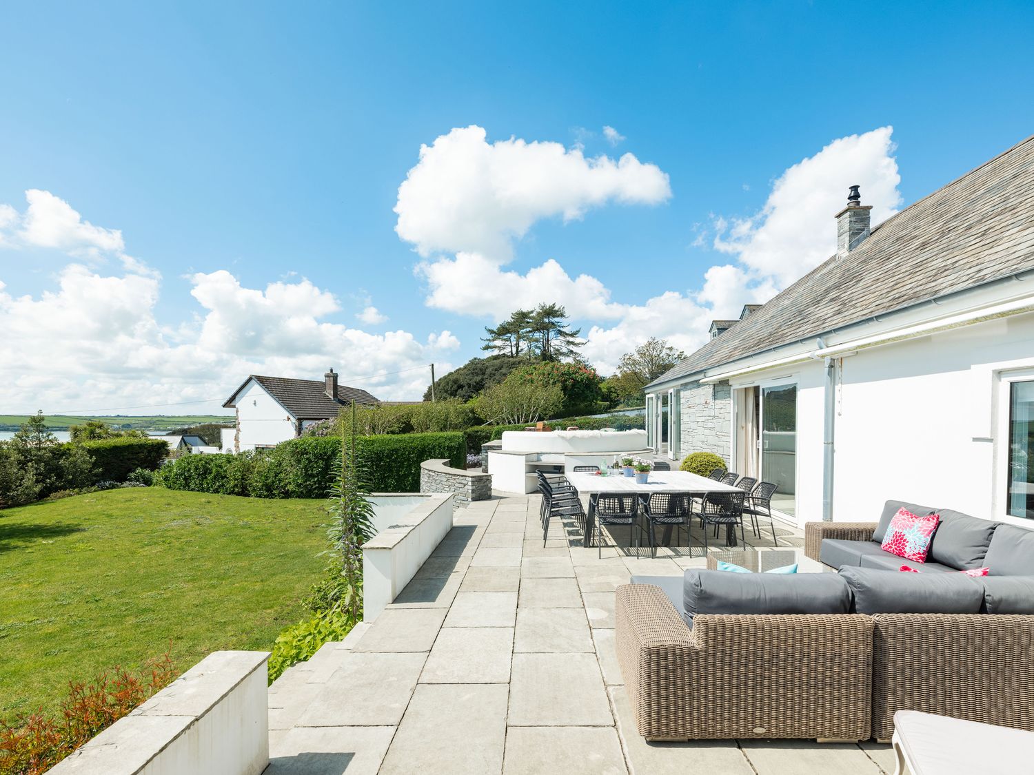 A patio with outdoor seating and dining area next to a white house with a lawn and trees at Landers Field Rock